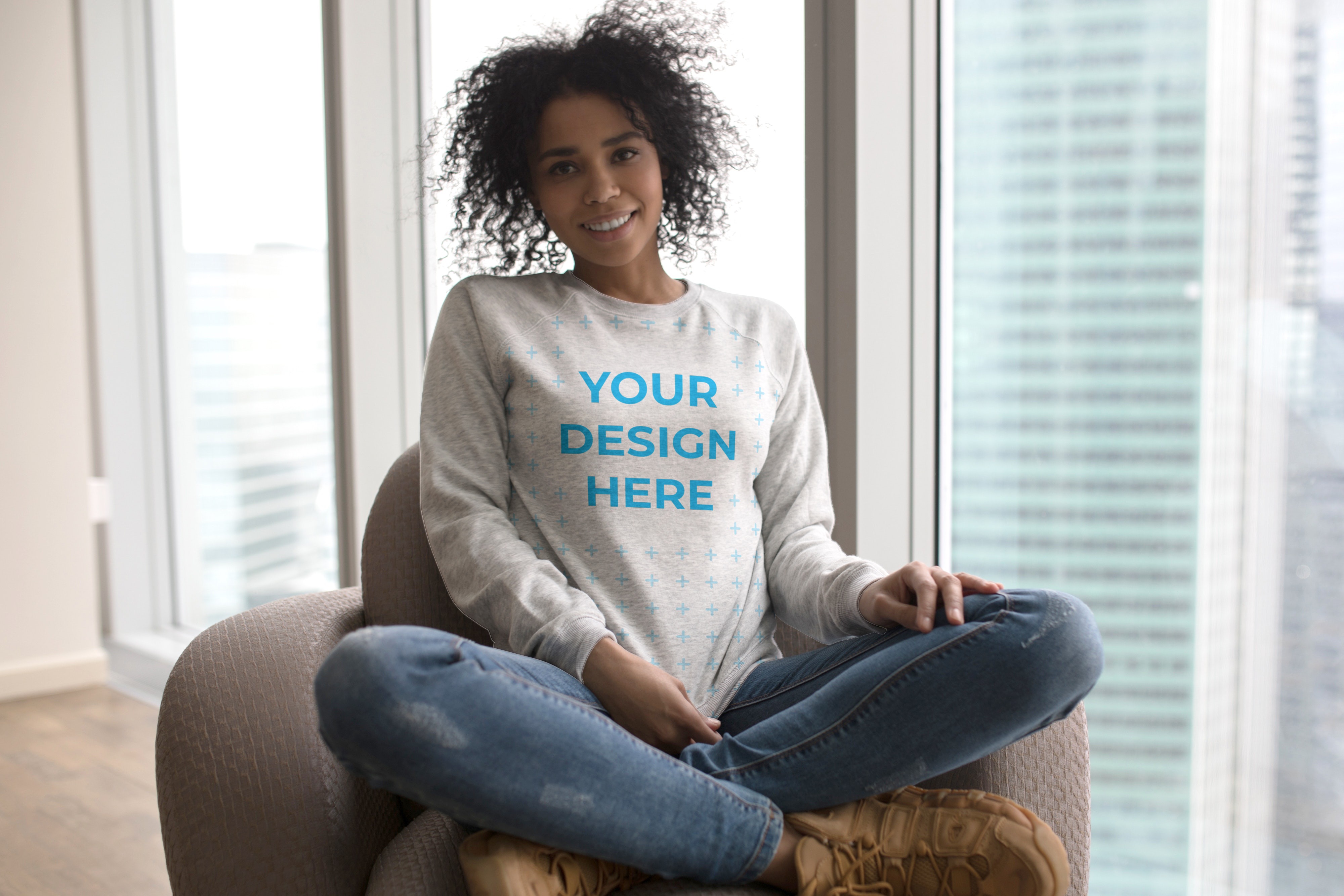 Download Free African-American woman wearing a sweatshirt near the window Mockup generator | Smartmockups